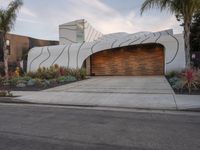 this driveway features a curved garage and decorative landscaping, which leads into the house's outdoor space