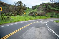 a curve in a country road with yellow lines going through the mountainside on the right