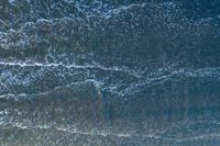 waves are rolling in a shallow pool near a beach at high tide and the sandy shore