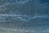 waves are rolling in a shallow pool near a beach at high tide and the sandy shore