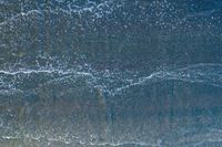 waves are rolling in a shallow pool near a beach at high tide and the sandy shore