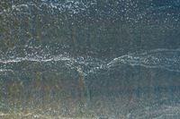 waves are rolling in a shallow pool near a beach at high tide and the sandy shore