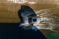 a vehicle drives through a body of water and in the sun, above the sidewalk