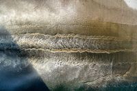 an aerial view of waves coming into the shore and a person standing on a surfboard