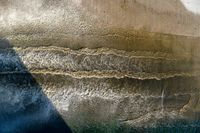 an aerial view of waves coming into the shore and a person standing on a surfboard