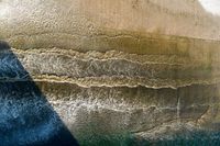 an aerial view of waves coming into the shore and a person standing on a surfboard