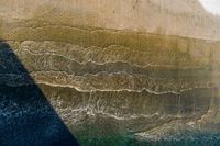 an aerial view of waves coming into the shore and a person standing on a surfboard