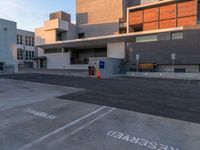 an empty parking space with large gray buildings in the background and white writing on it