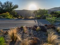 the sun shines over a small road near the mountains of the area of the desert