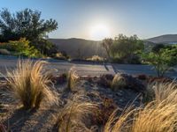 the sun shines over a small road near the mountains of the area of the desert