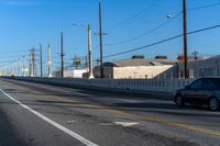 empty highway with stop sign and buildings in the distance on a sunny day next to an alley