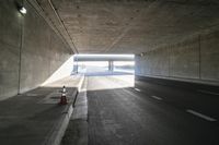 empty road with light and traffic going into tunnel in winter day, near highway sign