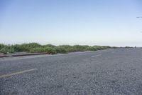 the view from the roadside of an empty road in rural countryside with grass growing around the median of the empty street