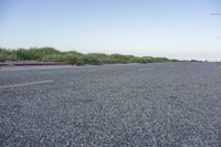 the view from the roadside of an empty road in rural countryside with grass growing around the median of the empty street