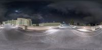 a big skate board park with lights reflecting off the concrete and clouds over it at night