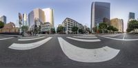 a group of people riding skateboards down a street next to tall buildings with curved shapes in the center