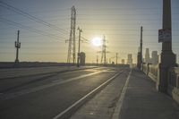 an empty highway with power lines leading to city buildings in the back ground and road tracks