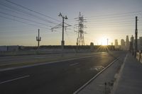 an empty highway with power lines leading to city buildings in the back ground and road tracks