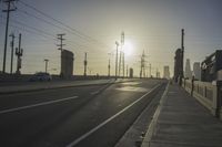 an empty highway with power lines leading to city buildings in the back ground and road tracks