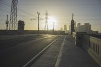 an empty highway with power lines leading to city buildings in the back ground and road tracks