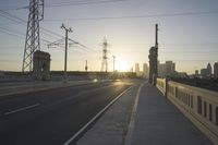 an empty highway with power lines leading to city buildings in the back ground and road tracks