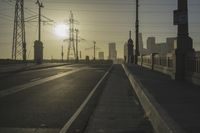 an empty highway with power lines leading to city buildings in the back ground and road tracks