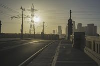 an empty highway with power lines leading to city buildings in the back ground and road tracks