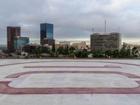 a concrete plaza with red and white lines in front of the skyline of a big city