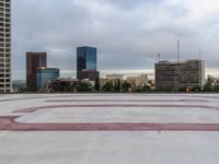 a concrete plaza with red and white lines in front of the skyline of a big city