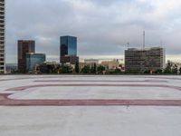 a concrete plaza with red and white lines in front of the skyline of a big city