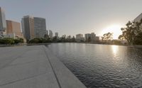 a city skyline with a lake and water feature near a path with buildings on either side