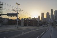 an empty highway with power lines leading to city buildings in the back ground and road tracks