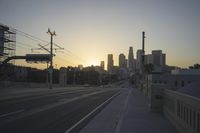 an empty highway with power lines leading to city buildings in the back ground and road tracks