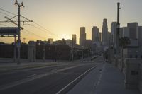 an empty highway with power lines leading to city buildings in the back ground and road tracks