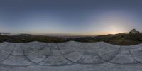 a picture of a curved ramp with the sun setting in the background and mountains in the distance