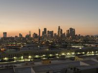 a big city skyline that is lit up at dusk in the background and pink sky