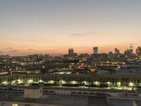 a big city skyline that is lit up at dusk in the background and pink sky