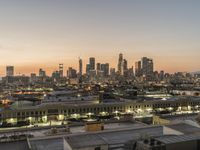 a big city skyline that is lit up at dusk in the background and pink sky