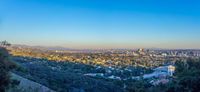 the sun shines on the city skyline from atop a hill in the hollywood district, california