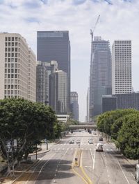 city with tall buildings and street signs on a busy road near some trees and a city street