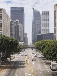 city with tall buildings and street signs on a busy road near some trees and a city street