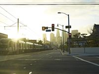 an empty highway with power lines leading to city buildings in the back ground and road tracks