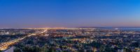 the city lights of oakland and downtown at twilight from above, near the water - front section of a city with a high rise