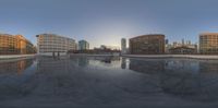 there is a reflection of some buildings in a puddle of water on the ground in front of an ice rink