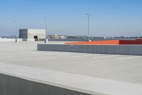 a small white building sitting on top of a cement ramp under a blue sky over a city