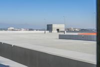 a small white building sitting on top of a cement ramp under a blue sky over a city