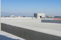 a small white building sitting on top of a cement ramp under a blue sky over a city