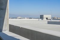 a small white building sitting on top of a cement ramp under a blue sky over a city