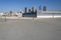 an empty parking lot in a city with skyscrapers in the background of this picture