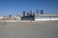 an empty parking lot in a city with skyscrapers in the background of this picture